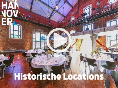 Festlich gedeckte Tische in einer historischen Backsteinhalle mit hohen Fenstern, Stahltr&auml;gern und moderner Beleuchtung.